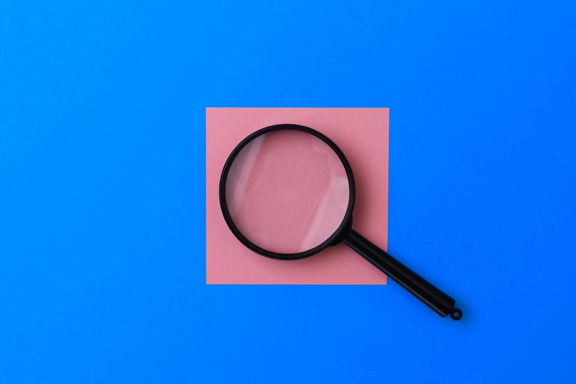 Lupa sobre quadrado rosa em fundo azul — auditoria heurística de usabilidade