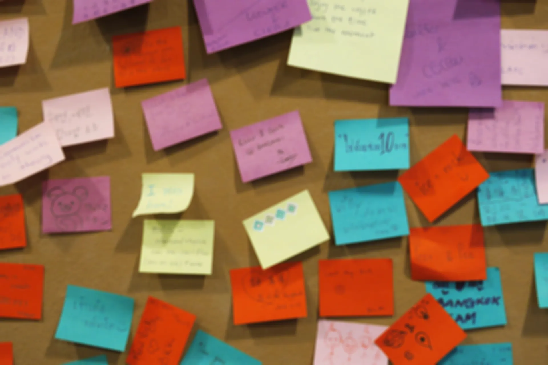 Post-its coloridos em quadro cortiça em workshop de discovery e priorização